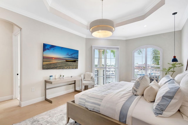 bedroom featuring a raised ceiling, wood-type flooring, and crown molding