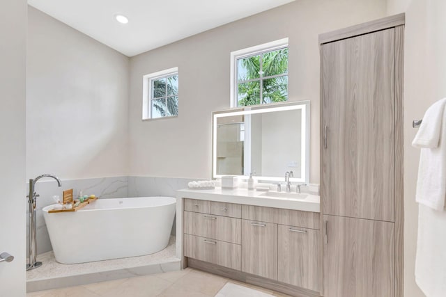 bathroom featuring a bathing tub, vanity, tile walls, and tile patterned flooring