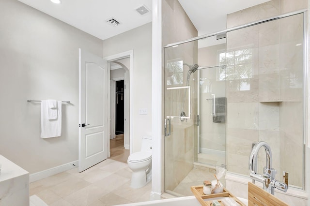 bathroom featuring tile patterned flooring, toilet, and walk in shower