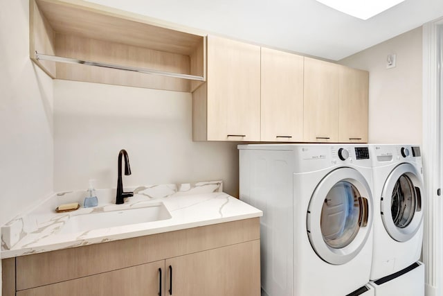 washroom with cabinets, separate washer and dryer, and sink