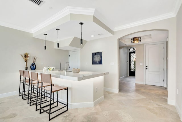 kitchen with sink, decorative light fixtures, a kitchen breakfast bar, and crown molding