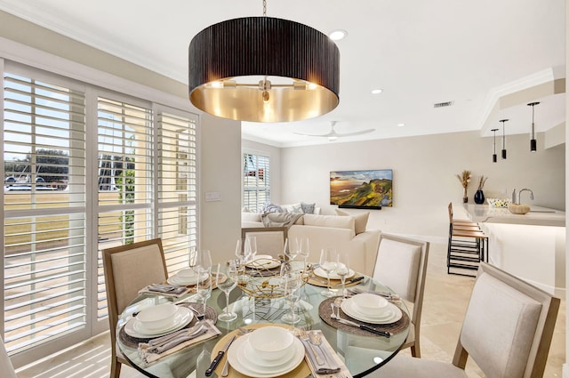 dining space with crown molding, sink, and ceiling fan