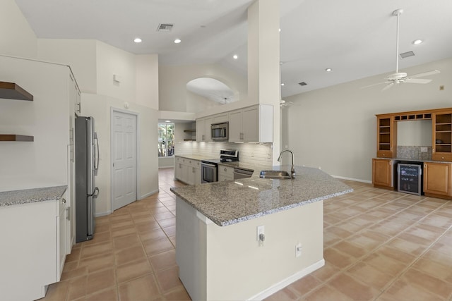 kitchen featuring beverage cooler, white cabinets, stainless steel appliances, sink, and kitchen peninsula