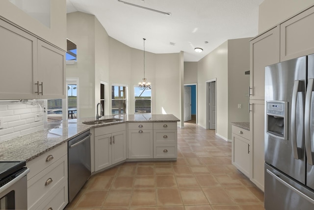 kitchen featuring appliances with stainless steel finishes, white cabinetry, sink, a notable chandelier, and light stone counters