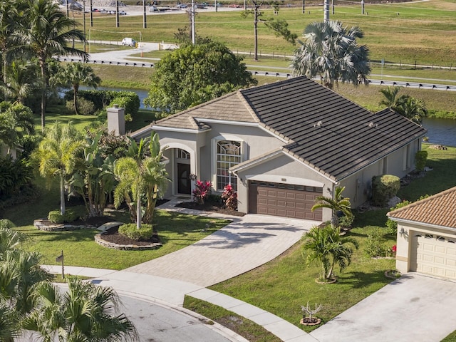 view of front of house featuring a water view, a front lawn, and a garage