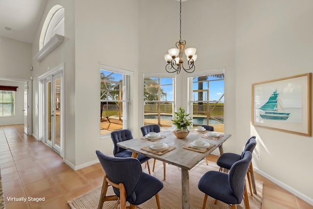 dining room with french doors, light tile patterned floors, a notable chandelier, and a towering ceiling