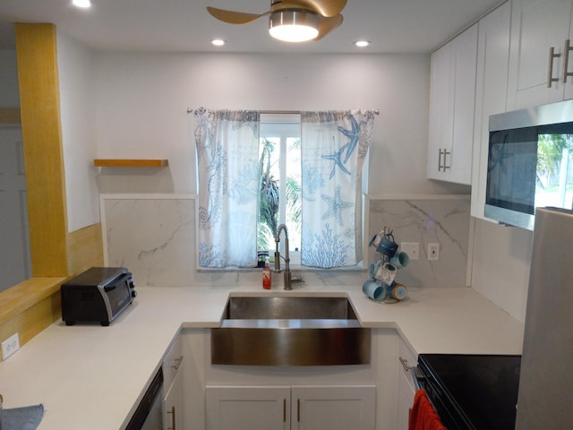 kitchen featuring backsplash, ceiling fan, sink, range, and white cabinetry