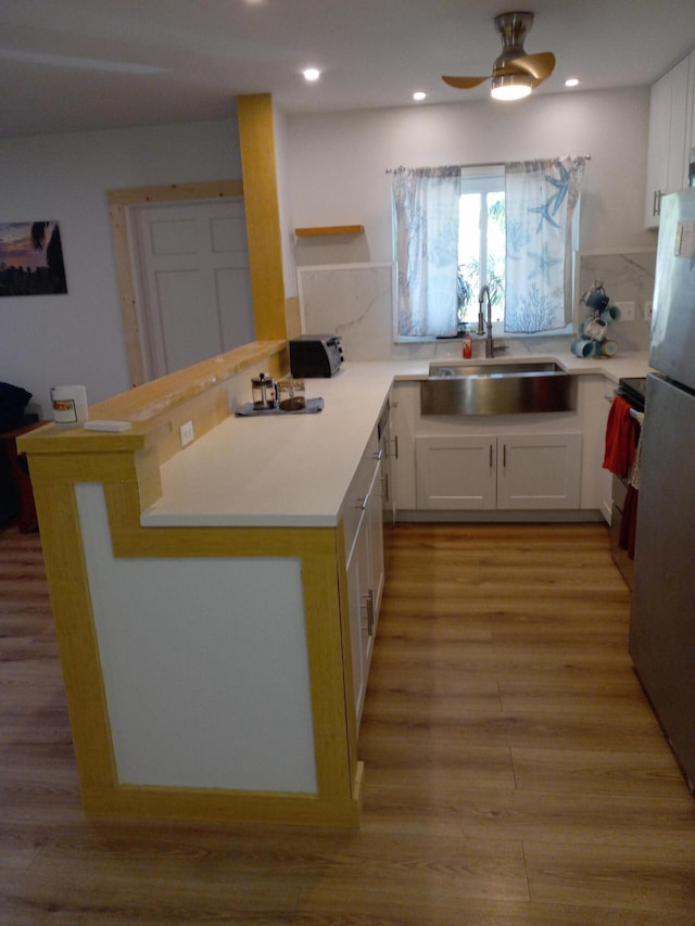 kitchen with white cabinets, stainless steel fridge, kitchen peninsula, and sink