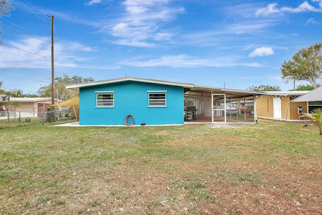 rear view of house featuring a sunroom and a yard