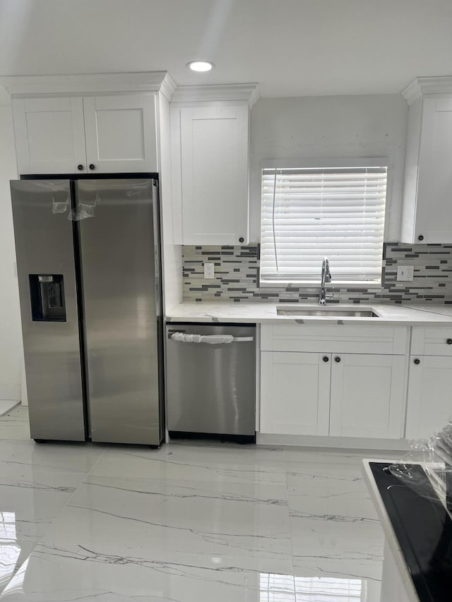 kitchen featuring appliances with stainless steel finishes, white cabinetry, backsplash, and sink