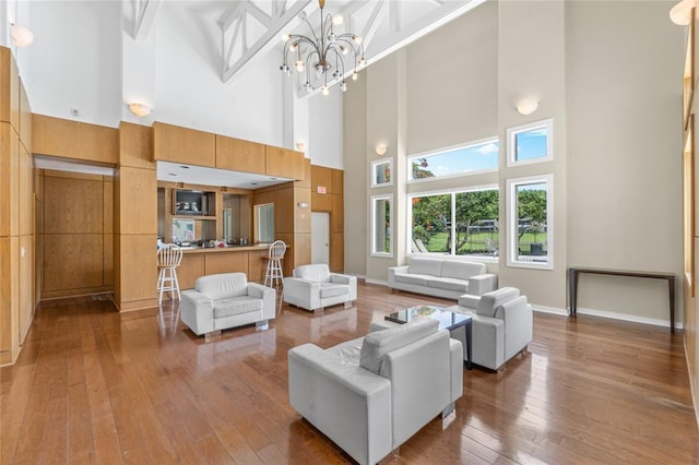 living room with hardwood / wood-style flooring, a towering ceiling, and a chandelier