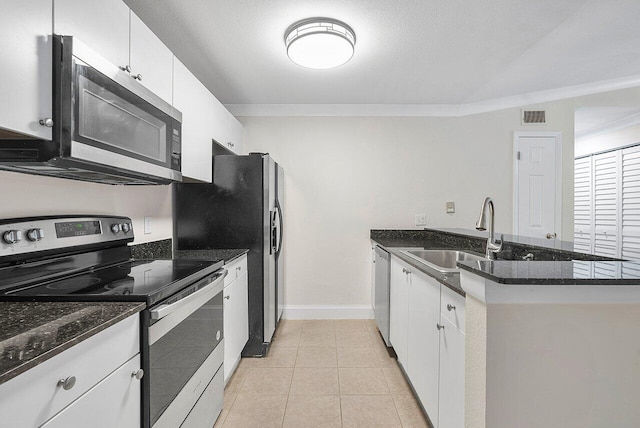 kitchen with stainless steel appliances, white cabinetry, dark stone counters, and sink