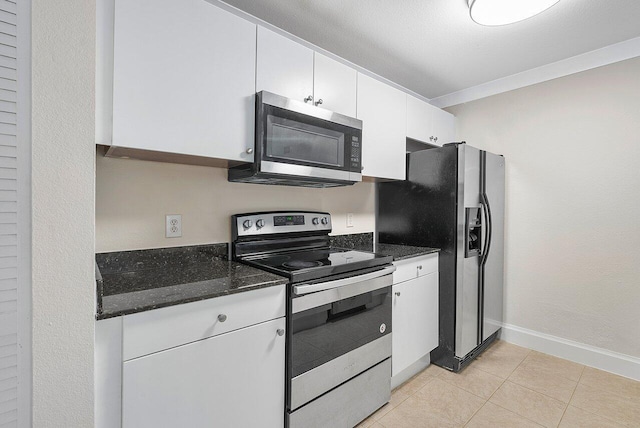 kitchen with dark stone counters, white cabinetry, light tile patterned flooring, and stainless steel appliances