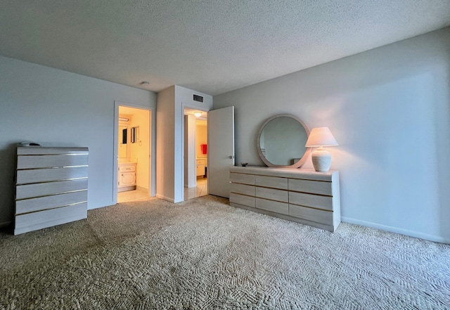 bedroom with a textured ceiling, light carpet, and connected bathroom