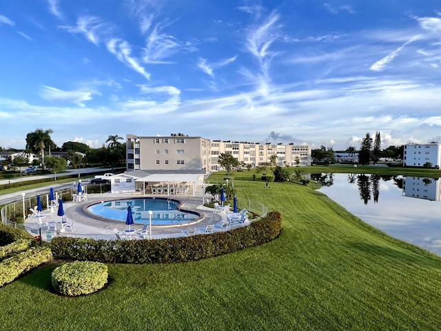 exterior space with a swimming pool, a water view, and a lawn