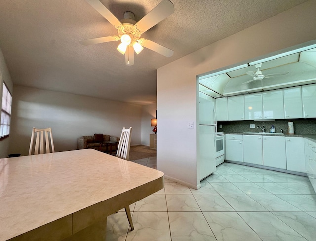 kitchen with ceiling fan, sink, tasteful backsplash, white appliances, and white cabinets