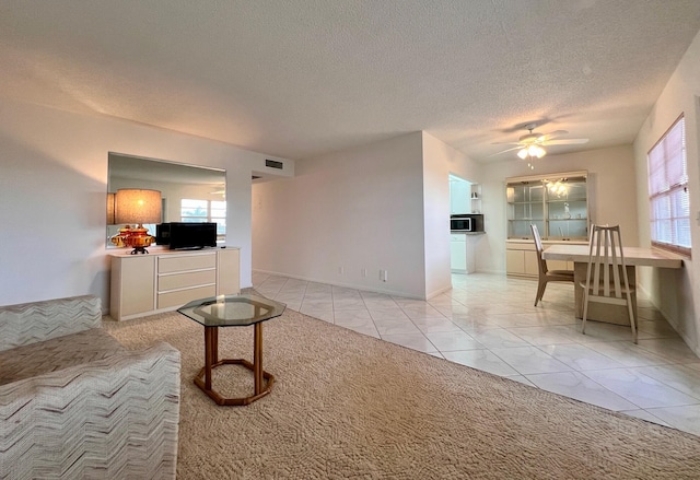 tiled living room featuring ceiling fan and a textured ceiling