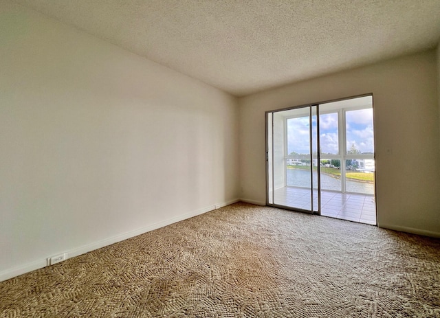 carpeted empty room featuring a textured ceiling and a water view