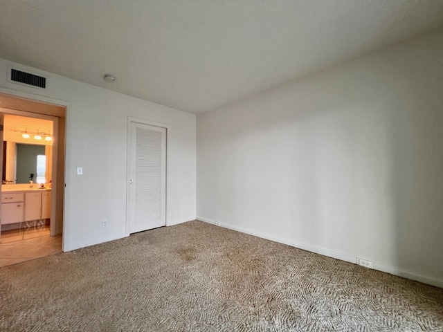 unfurnished bedroom with ensuite bathroom, carpet floors, and a closet