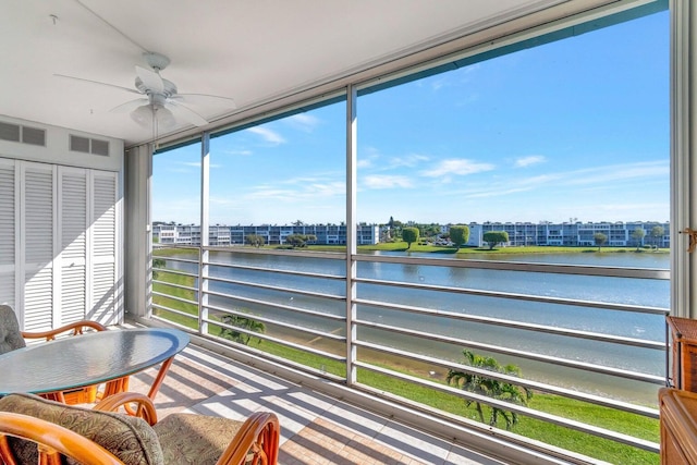 sunroom / solarium featuring a water view and ceiling fan