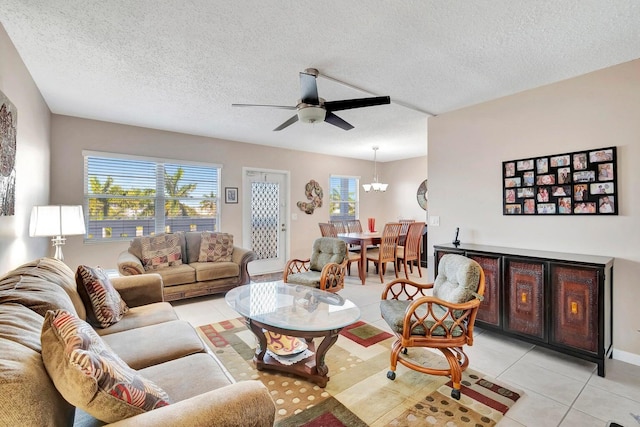 tiled living room with plenty of natural light, a textured ceiling, and ceiling fan with notable chandelier