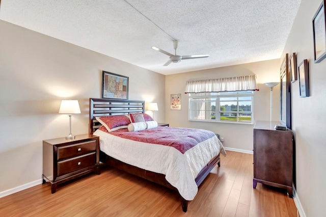 bedroom featuring ceiling fan, a textured ceiling, and light wood-type flooring