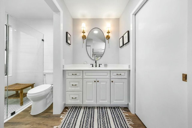 bathroom with an enclosed shower, vanity, tile walls, hardwood / wood-style floors, and toilet