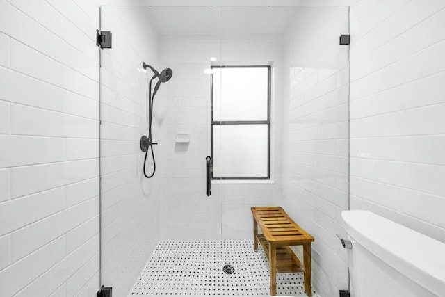 bathroom featuring a shower with shower door and toilet