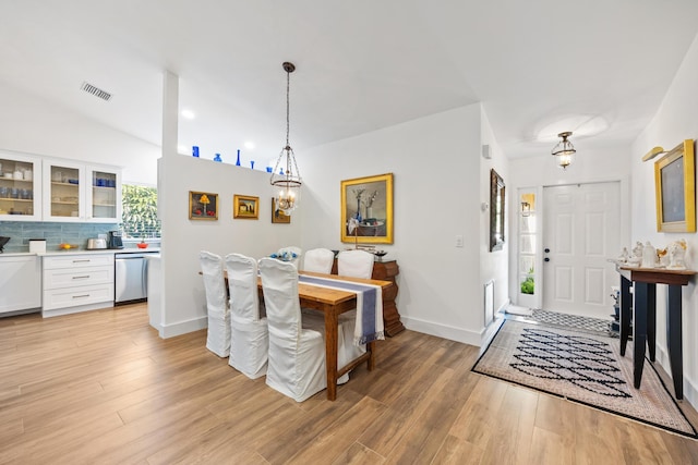 dining space with lofted ceiling, light hardwood / wood-style flooring, and a notable chandelier