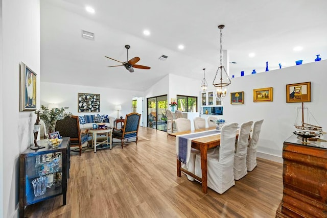 dining room with ceiling fan with notable chandelier, lofted ceiling, and hardwood / wood-style flooring