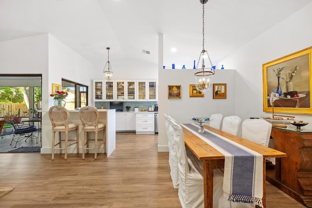 dining room featuring a chandelier, lofted ceiling, and light wood-type flooring