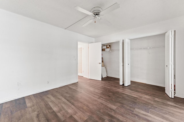 unfurnished bedroom with multiple closets, ceiling fan, and dark wood-type flooring