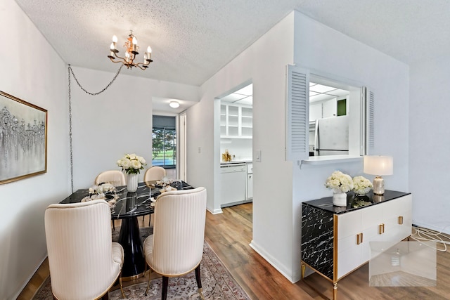 dining space with a chandelier, a textured ceiling, and hardwood / wood-style flooring