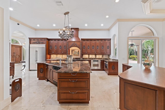 kitchen featuring appliances with stainless steel finishes, backsplash, crown molding, pendant lighting, and a center island with sink