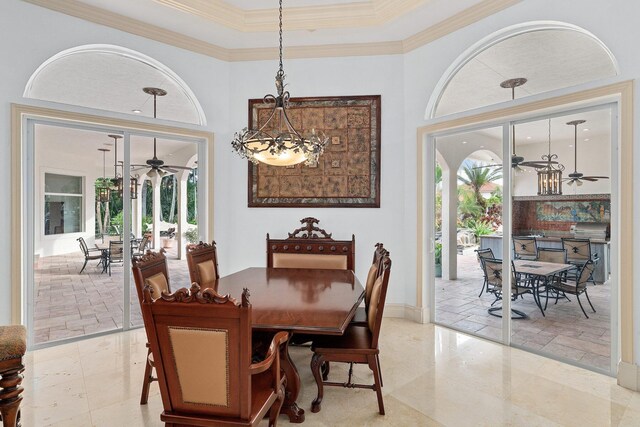 dining space featuring ceiling fan with notable chandelier, a towering ceiling, and crown molding