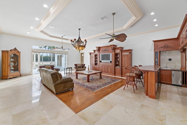 living room featuring ceiling fan with notable chandelier, light hardwood / wood-style floors, ornamental molding, and a tray ceiling