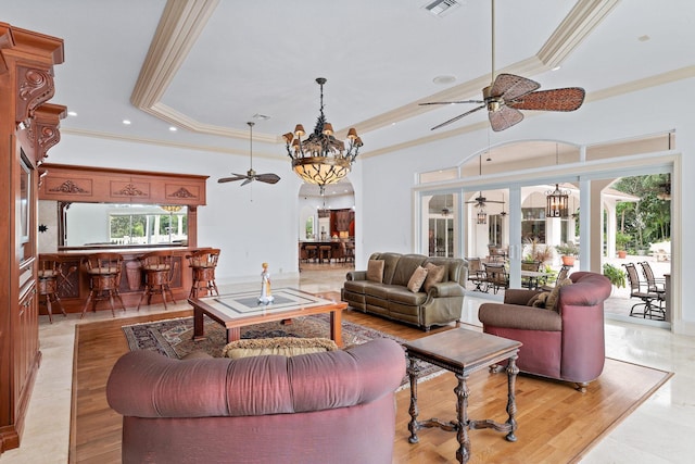 living room featuring a raised ceiling, crown molding, and ceiling fan with notable chandelier