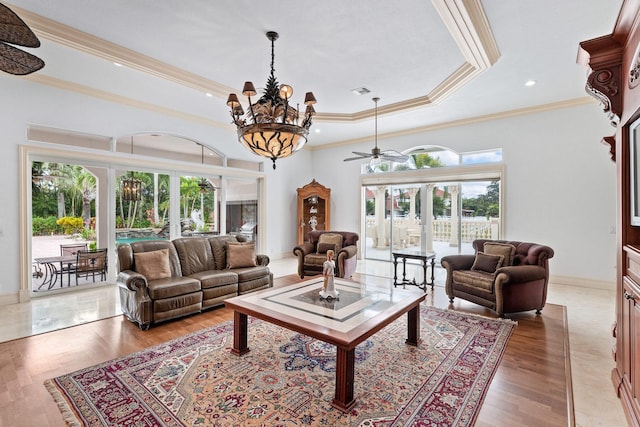 living room with hardwood / wood-style floors, ceiling fan with notable chandelier, crown molding, and a tray ceiling