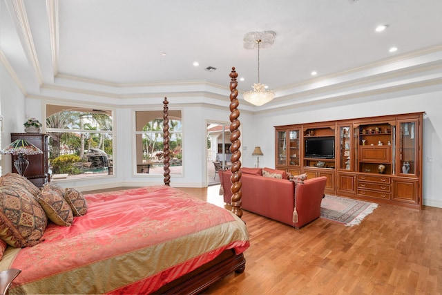 bedroom featuring crown molding, light hardwood / wood-style flooring, and a tray ceiling