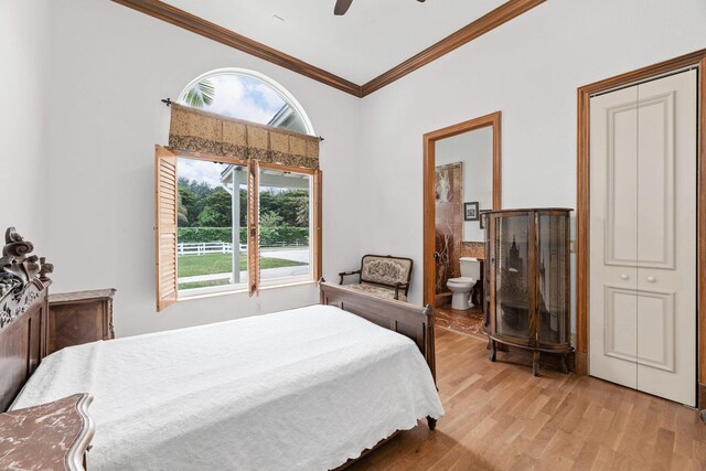 bedroom featuring light wood-type flooring, ensuite bath, ceiling fan, and crown molding