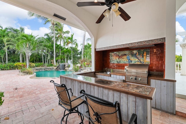 view of patio / terrace featuring ceiling fan, area for grilling, grilling area, and a wet bar