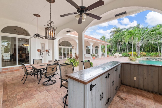 view of patio with ceiling fan and a bar