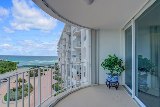 balcony with a water view and a view of the beach