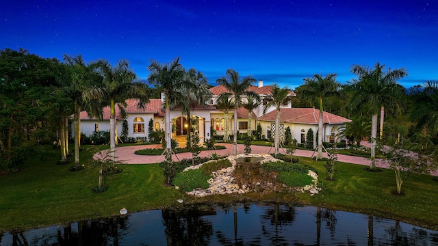 mediterranean / spanish house featuring a water view and a yard