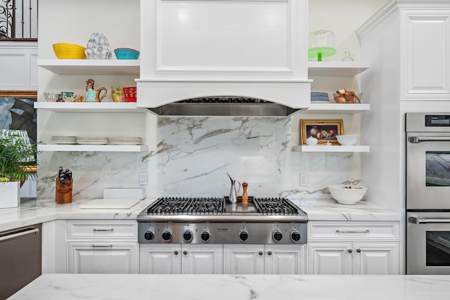 kitchen featuring light stone countertops, appliances with stainless steel finishes, white cabinets, and decorative backsplash