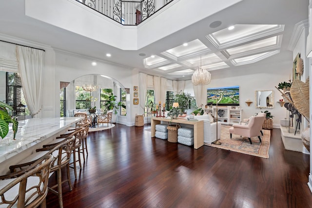 living room featuring dark hardwood / wood-style floors, a high ceiling, coffered ceiling, a notable chandelier, and ornamental molding