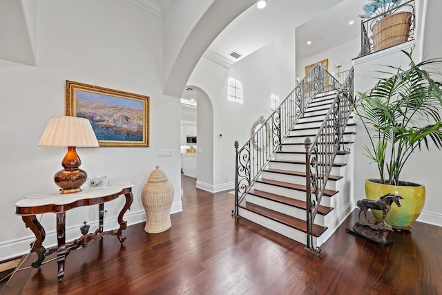 foyer featuring hardwood / wood-style flooring, a towering ceiling, and ornamental molding