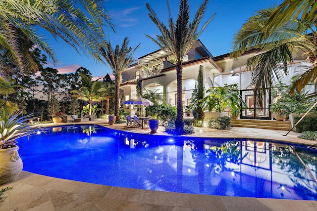 pool at dusk featuring a patio area