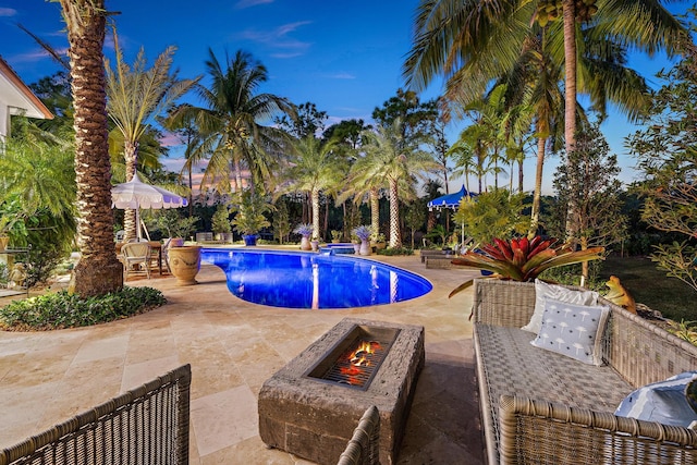 pool at dusk with a patio and a fire pit