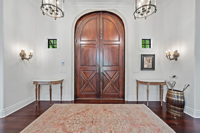 foyer entrance featuring dark hardwood / wood-style flooring, crown molding, and a chandelier